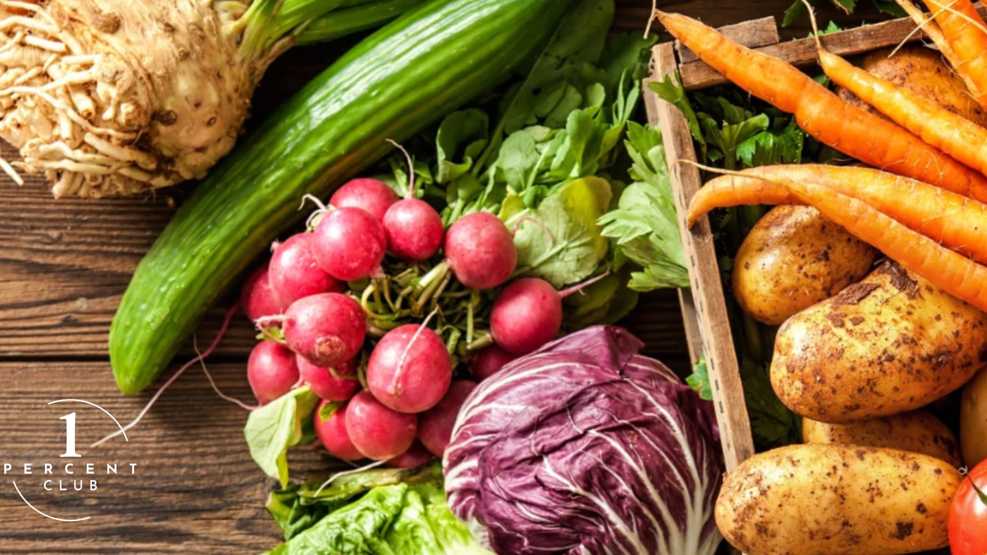 A crate of raw vegetables: radishes, cucumber, carrots, potatoes, celeriac and radicchio