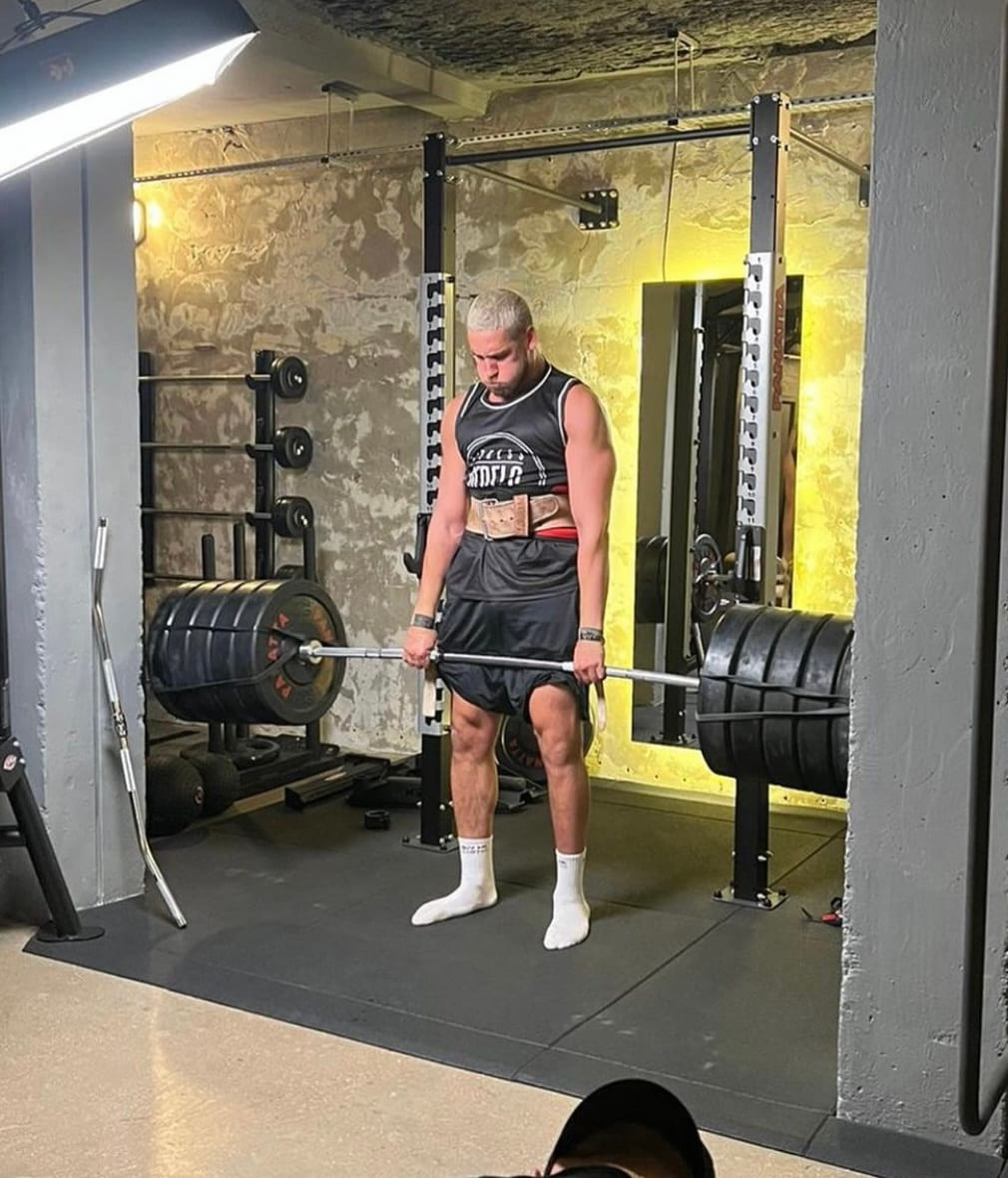 A lifter setting up over a loaded barbell in a basement gym