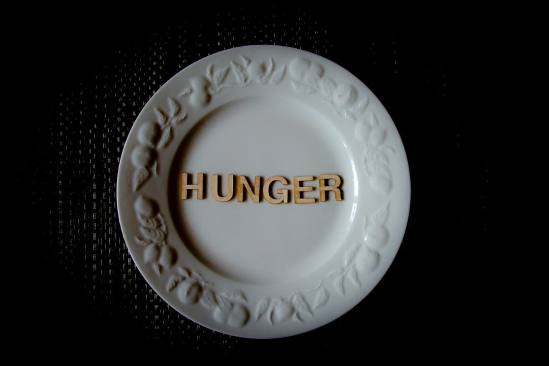 An empty white plate with the word hunger set into it