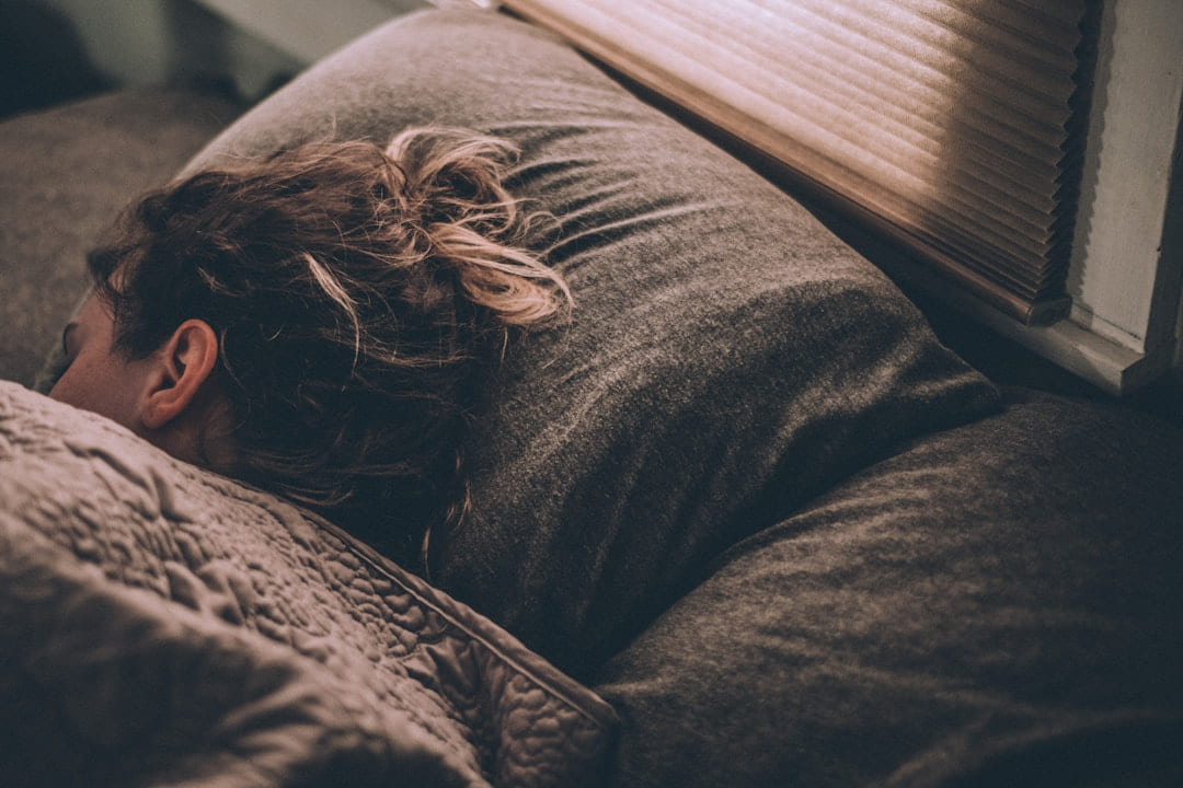 Someone sleeping face down in bed in dim light