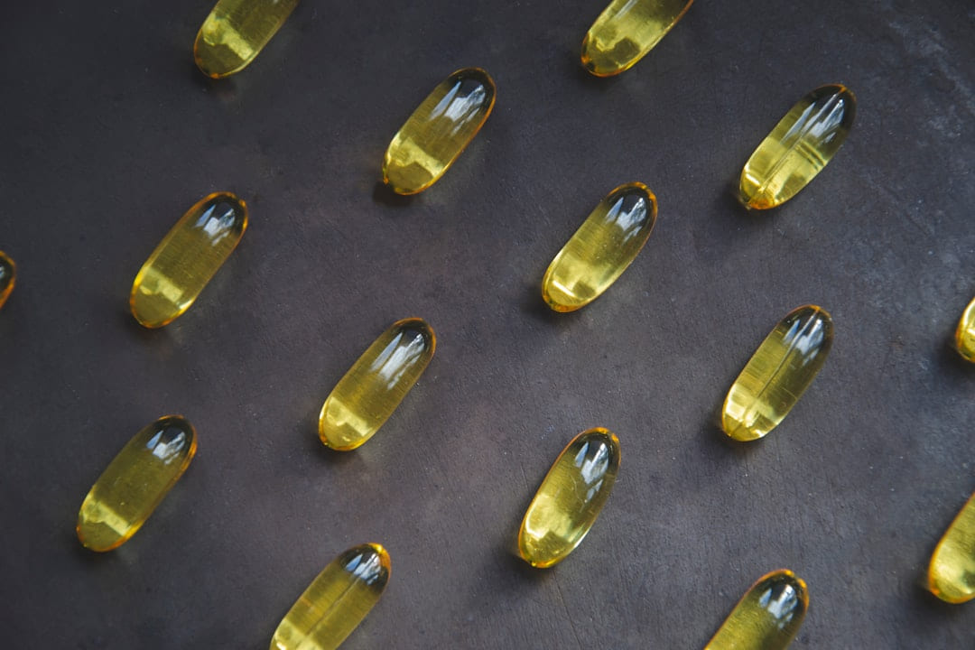 Rows of golden fish oil capsules on a dark surface
