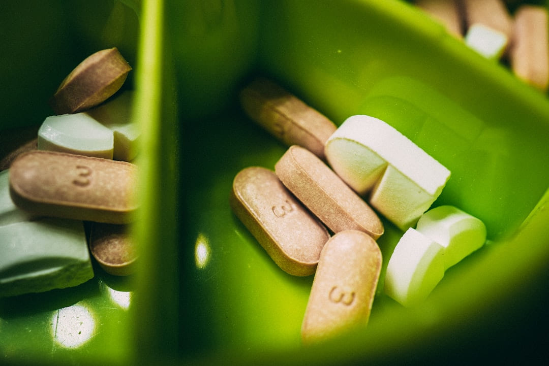 Assorted tablets and capsules in a green pill container