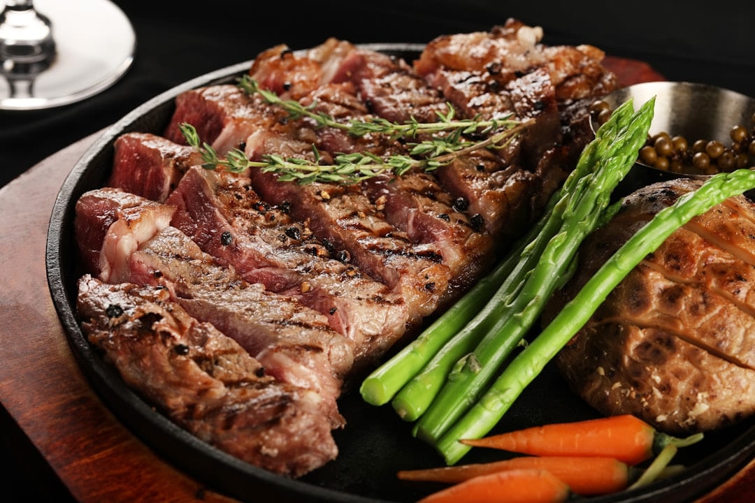 Sliced steak with asparagus and carrots in a cast iron pan