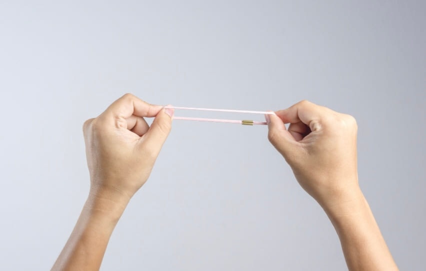 Two hands stretching a rubber band until it is taut