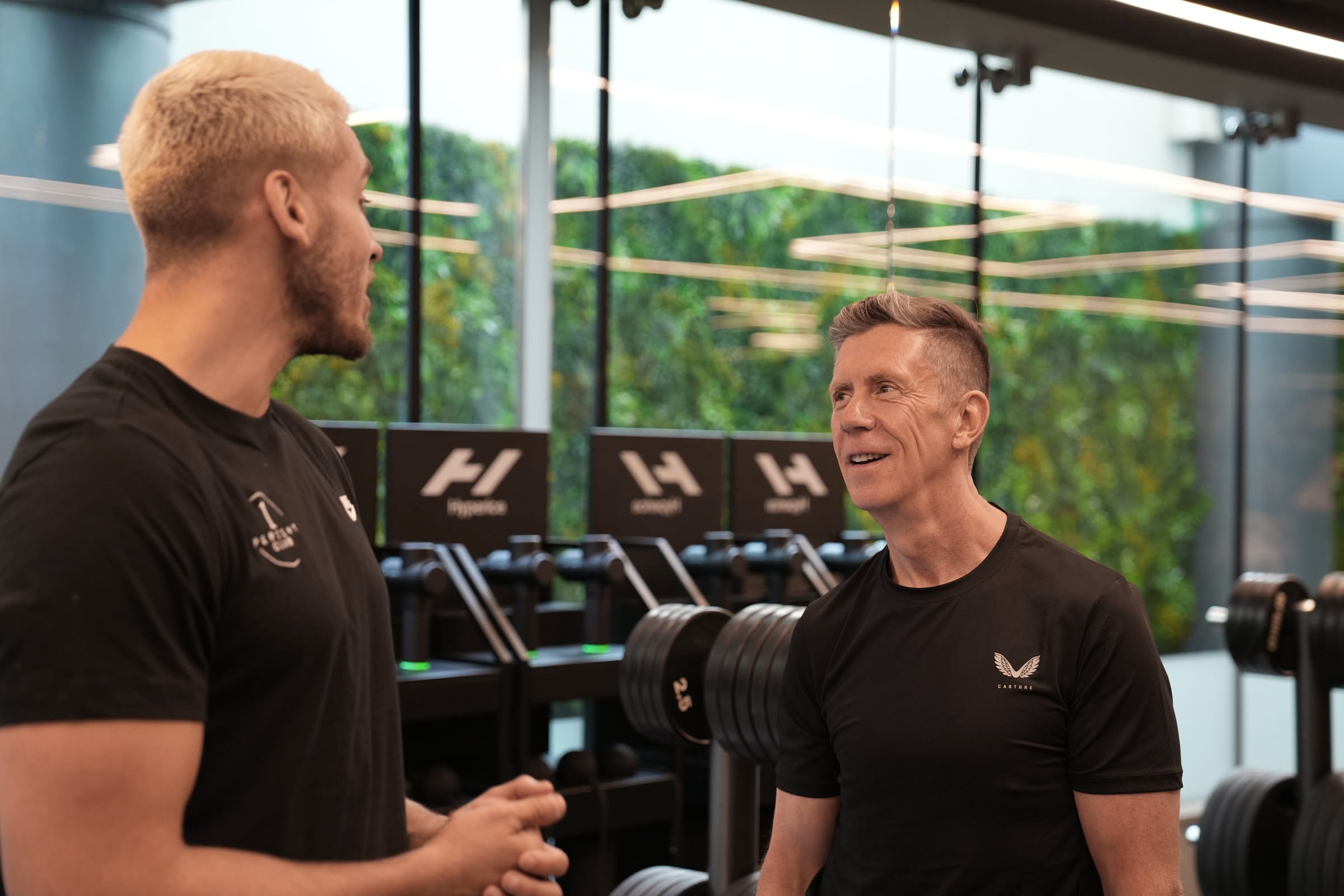 A coach and client talking on the training floor between sets